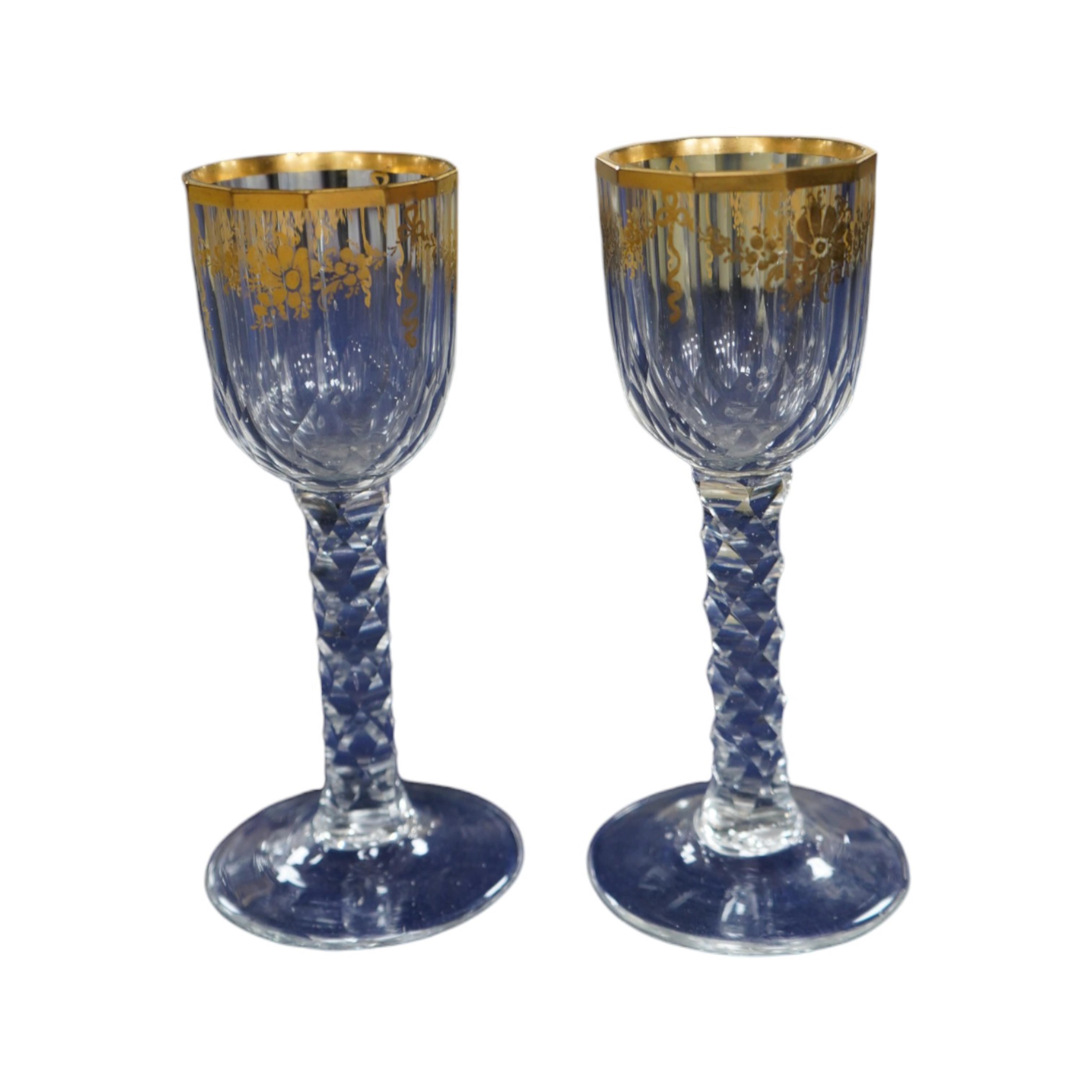 A pair of early 18th century octagonal glasses with gilt floral swagged decoration and facetted stems. Condition - slight wear to gilding otherwise good